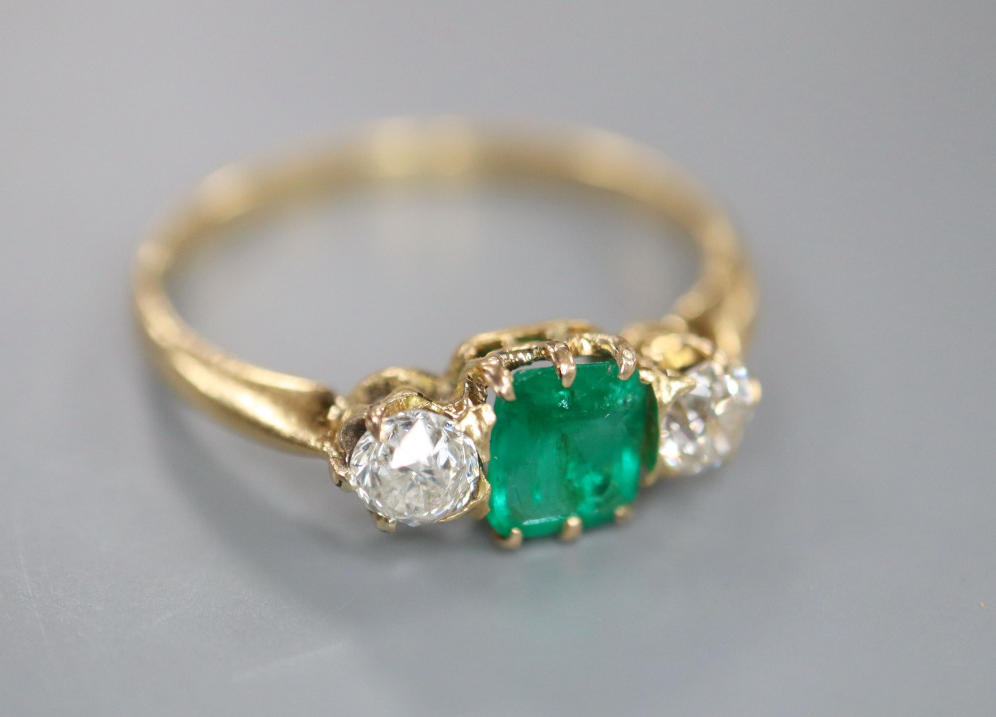 A yellow metal, emerald and diamond three stone ring, size Q, gross 2.3 grams.